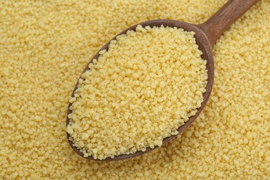 Photo of Spoon with raw couscous as background, top view