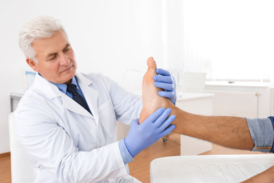 Male orthopedist checking patient's foot in clinic