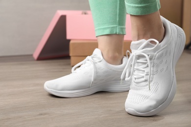 Photo of Woman wearing stylish sport shoes indoors, closeup