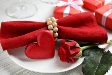 Photo of Beautiful place setting with decorative heart on white wooden table, closeup view. Valentine's day romantic dinner