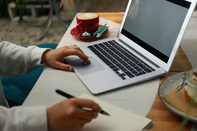 Photo of Blogger working with laptop in cafe, closeup