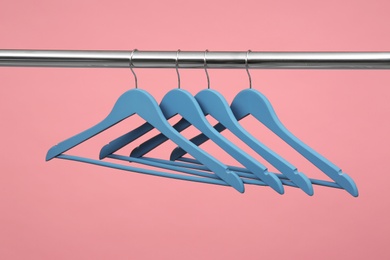 Photo of Empty clothes hangers on metal rail against color background