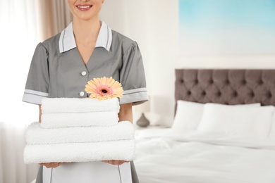 Photo of Chambermaid with stack of fresh towels in hotel room, closeup. Space for text