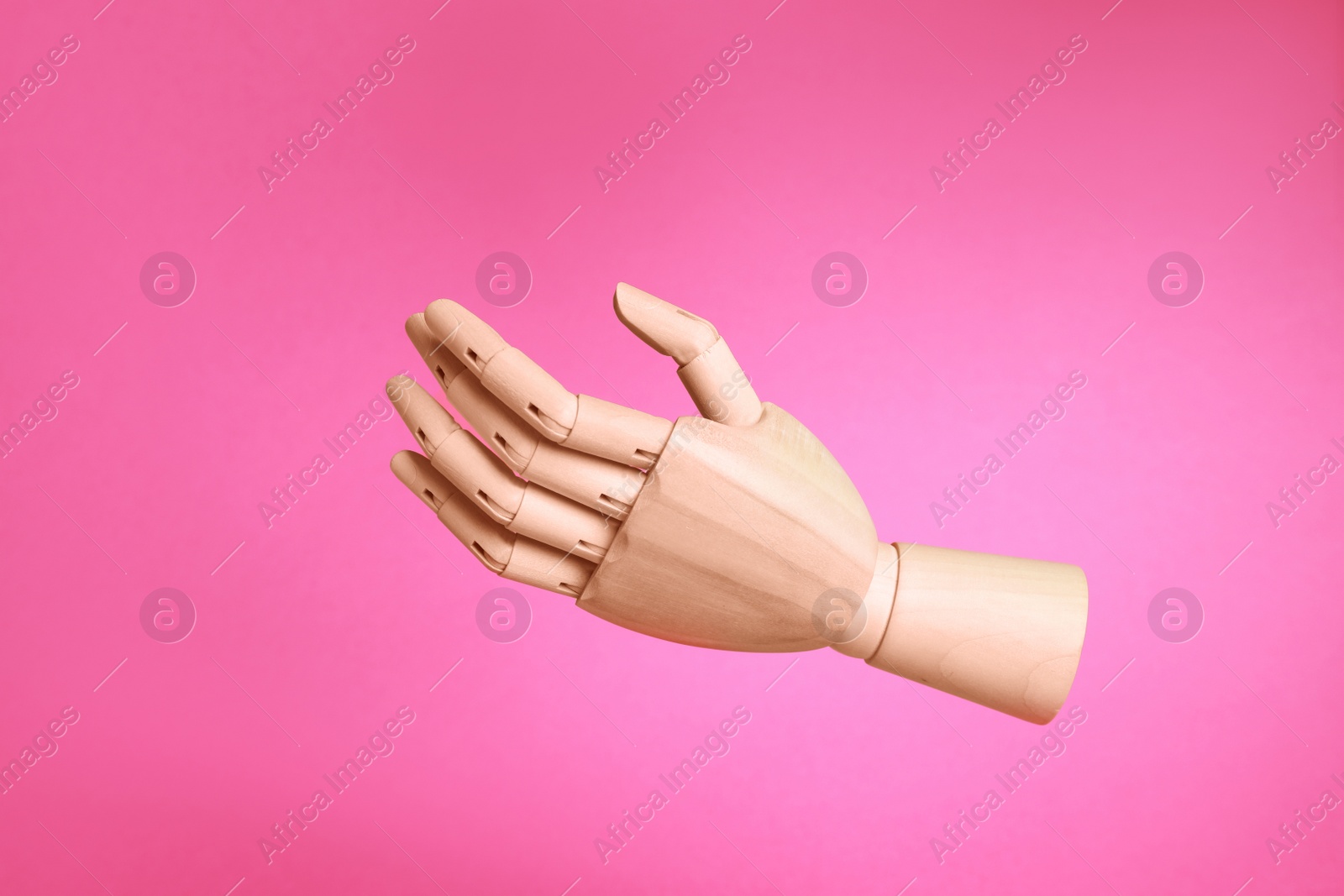 Photo of Wooden hand model on pink background. Mannequin part