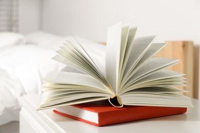 Books on white wooden bedside table in bedroom