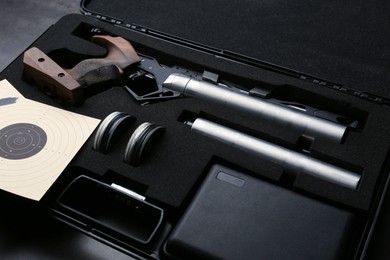 Photo of Case with sport pistol and accessories on black table. Professional gun