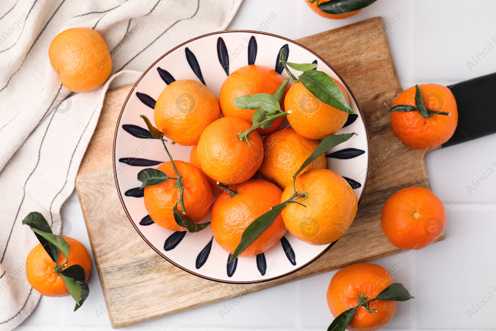 Photo of Fresh ripe tangerines with green leaves on white tiled table, flat lay