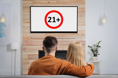 Image of Couple watching TV with age limit sign 21+ years in living room