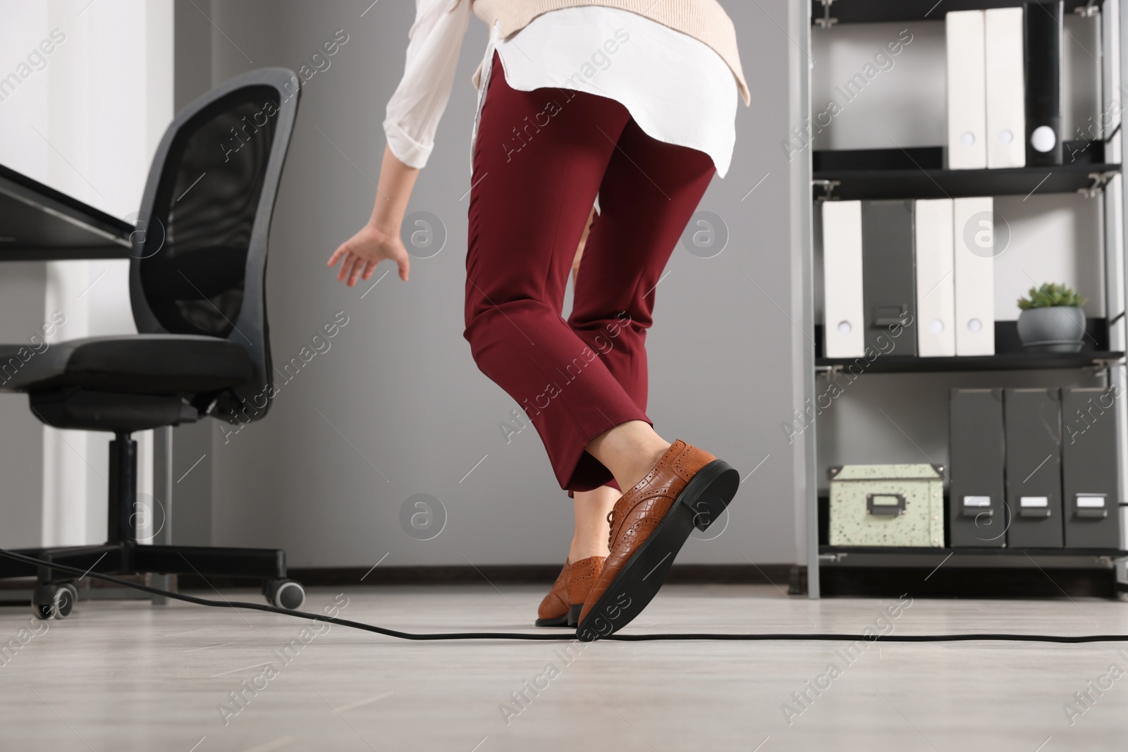 Photo of Woman tripping over cable in office, closeup