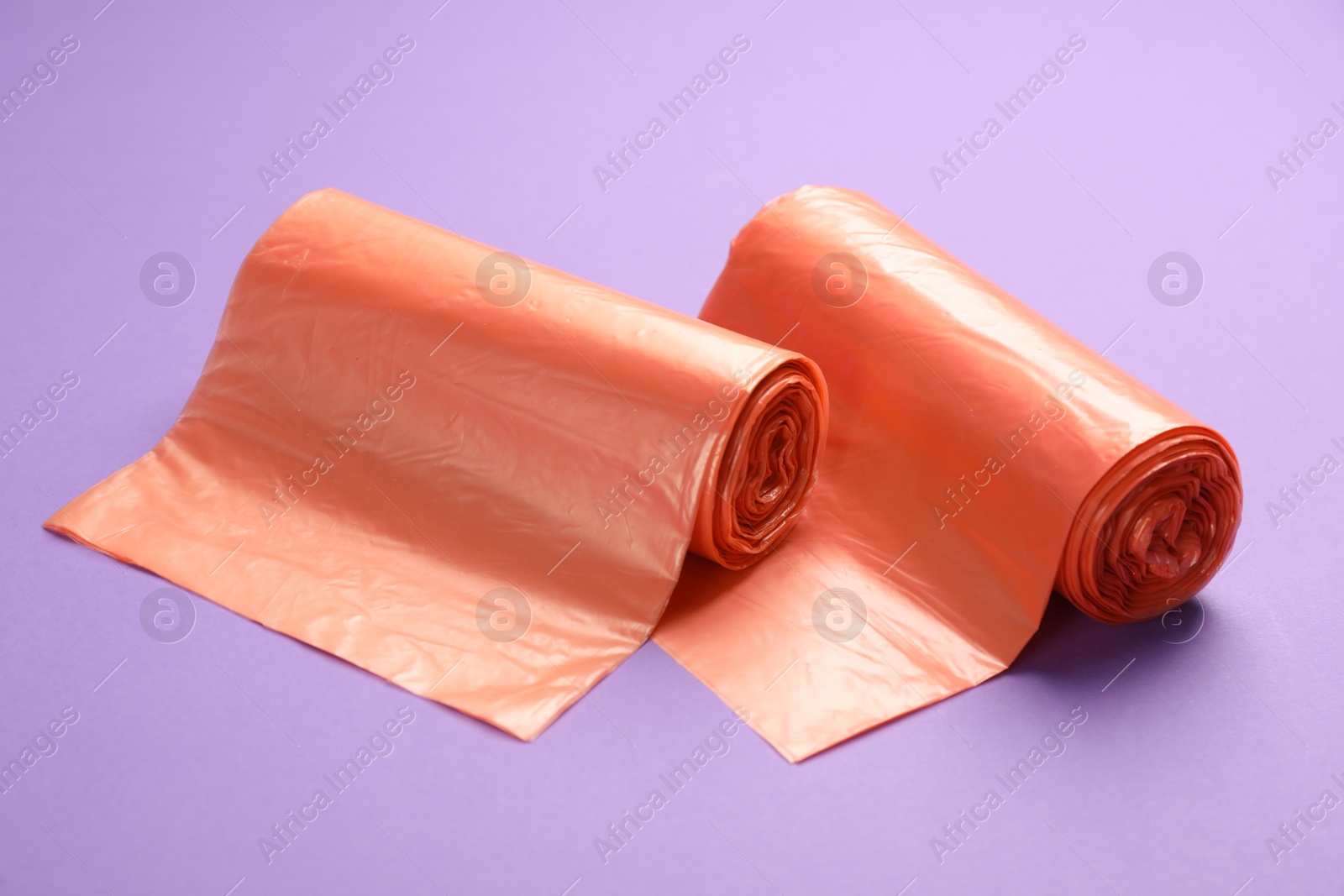 Photo of Rolls of orange garbage bags on violet background