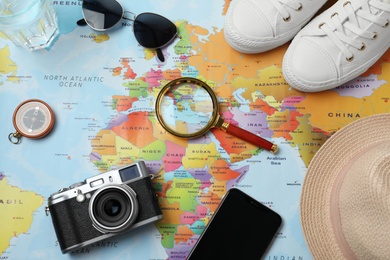 Photo of Flat lay composition with different travel accessories on world map. Planning summer vacation trip