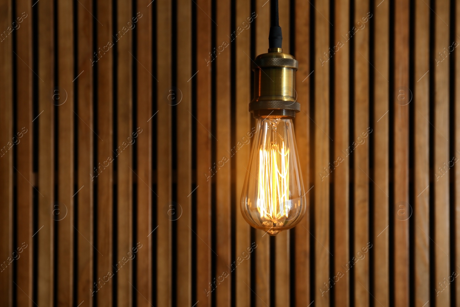 Photo of Pendant lamp with light bulb on wooden background. Space for text