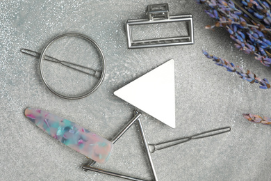 Photo of Stylish hair clips and flowers on grey table, flat lay