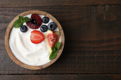 Photo of Bowl with yogurt, berries, fruits and mint on wooden table, top view. Space for text