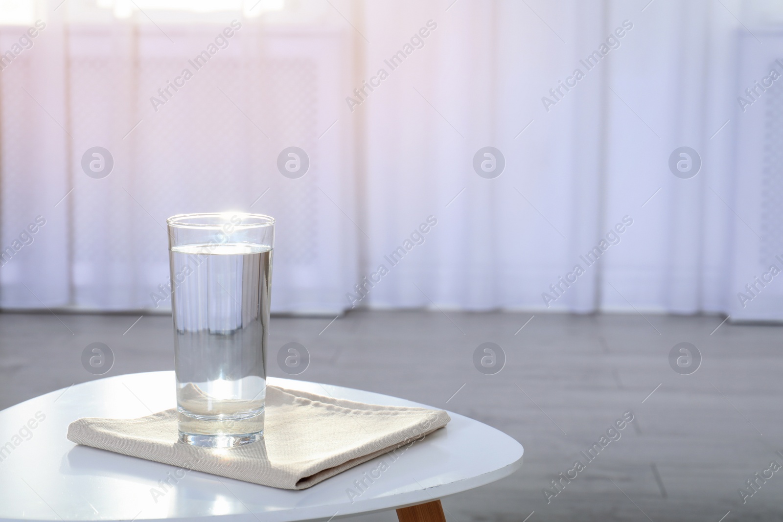 Photo of Glass of water on table against blurred background. Space for text