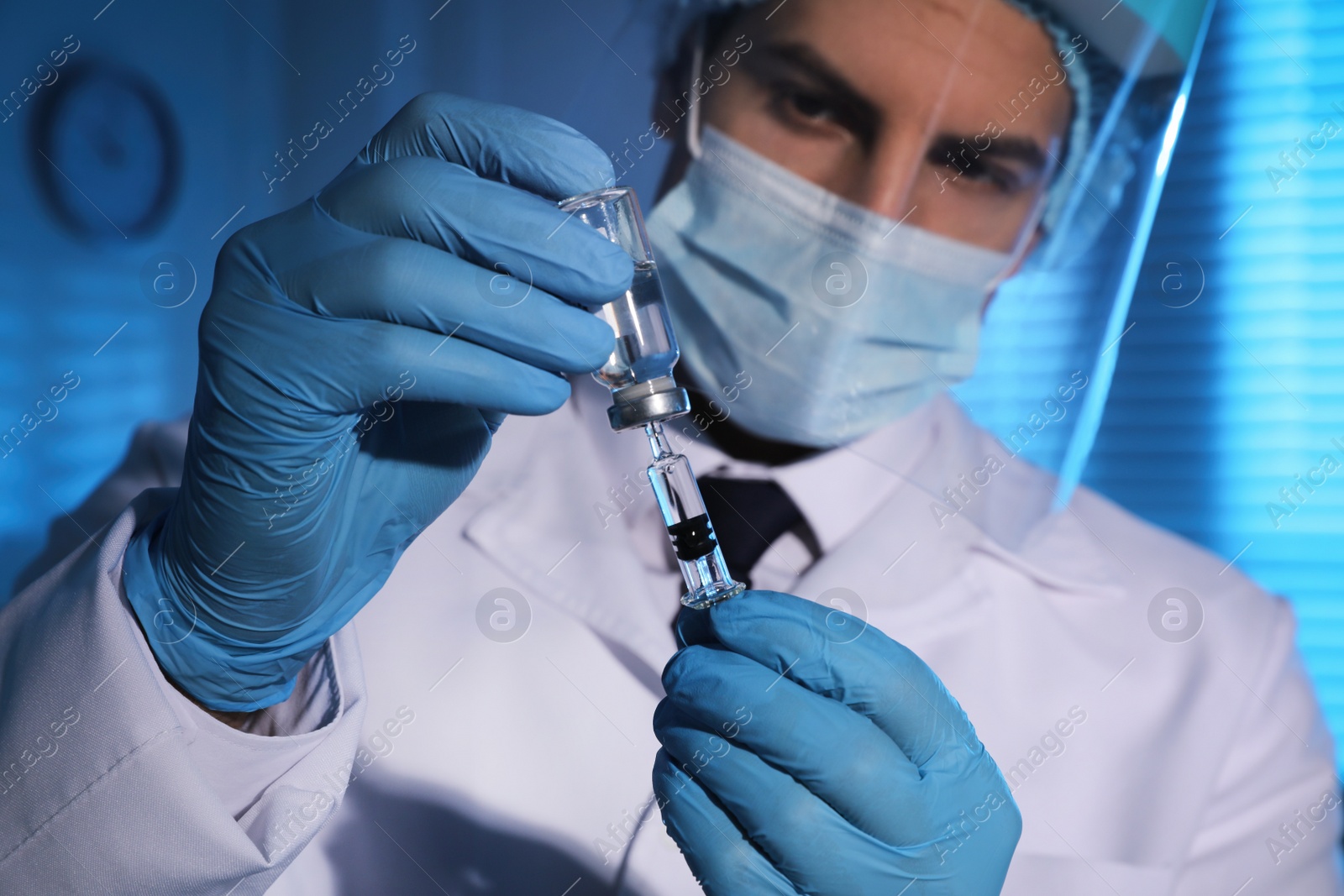 Photo of Doctor filling syringe with vaccine against Covid-19 in laboratory, focus on hands