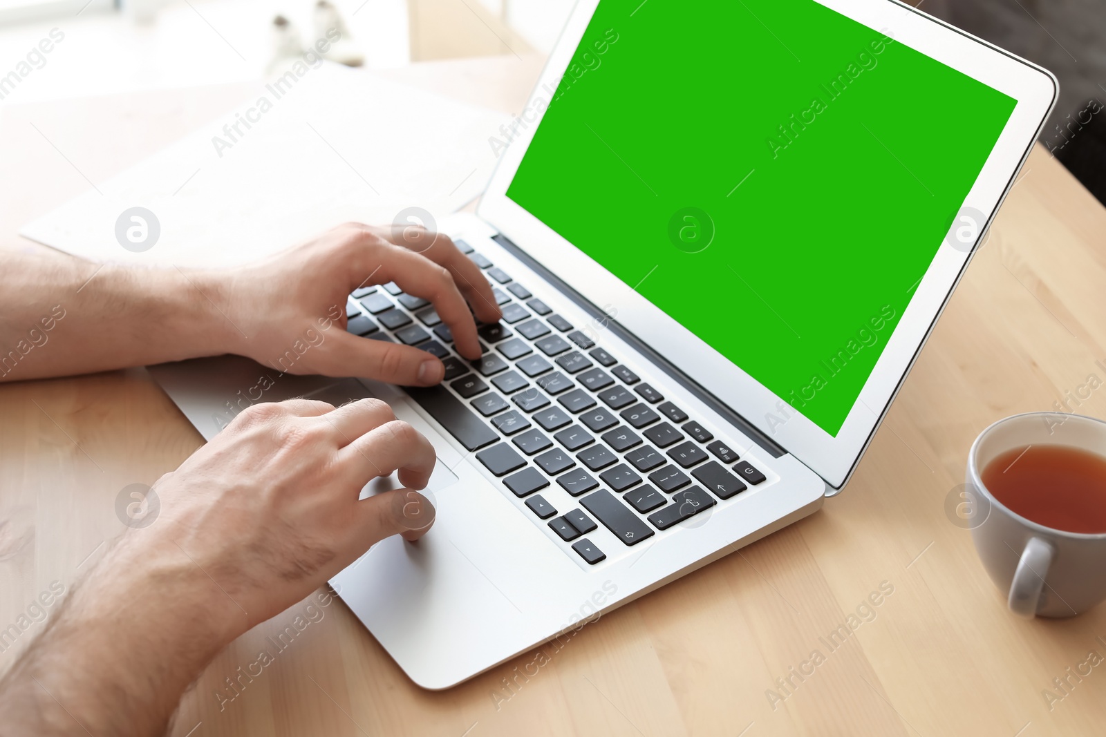 Image of Young man using laptop at desk, closeup. Device display with chroma key