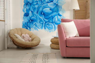 Photo of Stylish living room with blue flowers painted on wall. Floral pattern in interior design