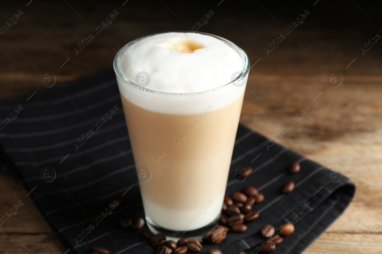 Photo of Delicious latte macchiato and coffee beans on wooden table