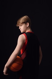 Photo of Teenage boy with basketball ball on black background