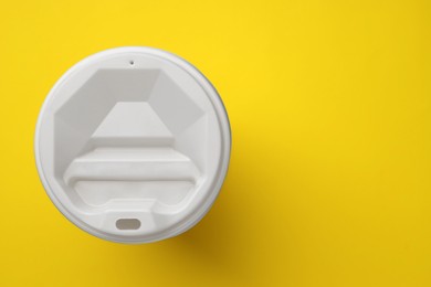 One paper cup with white lid on yellow background, top view with space for text. Coffee to go