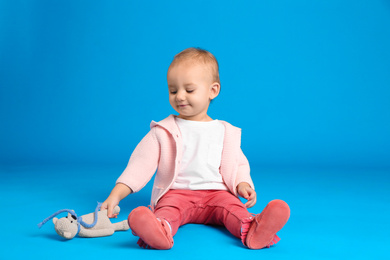 Photo of Cute little child playing with knitted toy on light blue background