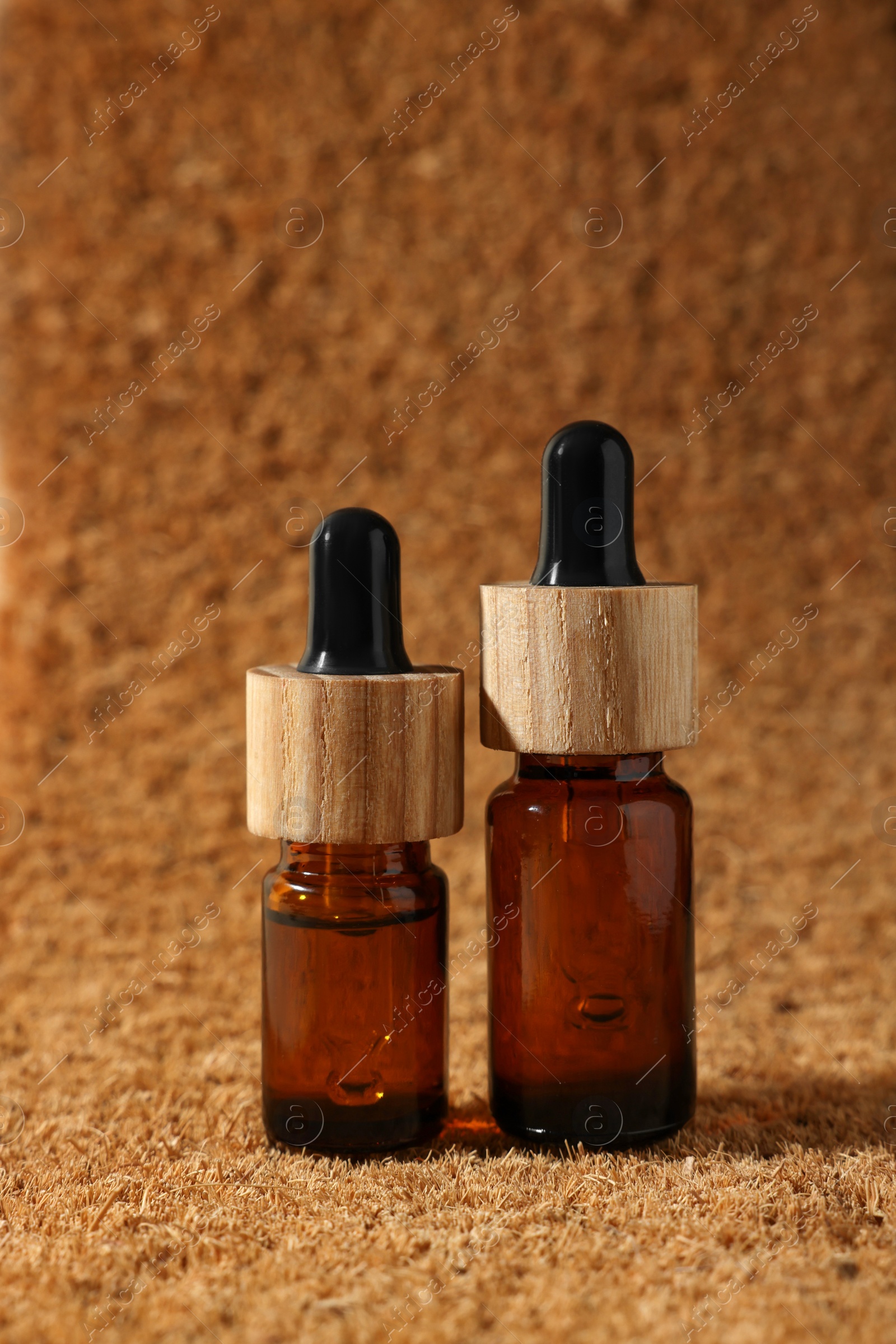 Photo of Bottles of essential oil on brown textured background