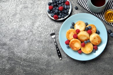 Photo of Delicious cottage cheese pancakes with fresh berries and honey on grey table, flat lay. Space for text
