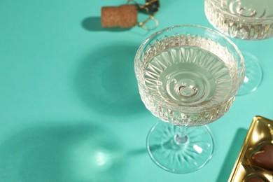 Photo of Glasses of expensive white wine on turquoise background. Space for text