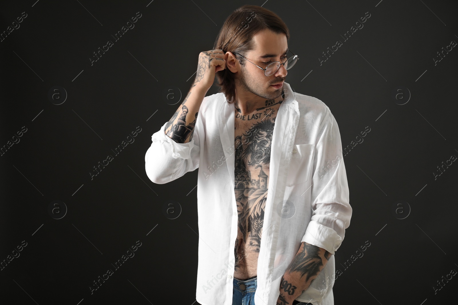 Photo of Young man with tattoos on body against black background