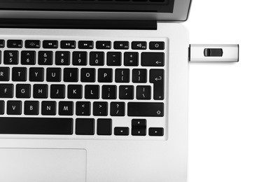Modern usb flash drive attached into laptop on white background, top view