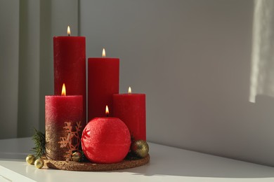 Photo of Burning candles with Christmas decor on white table. Space for text