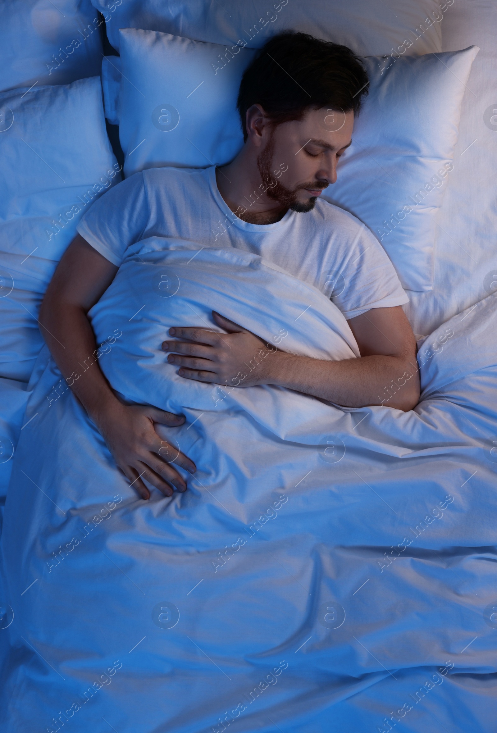 Photo of Man sleeping in bed at night, above view