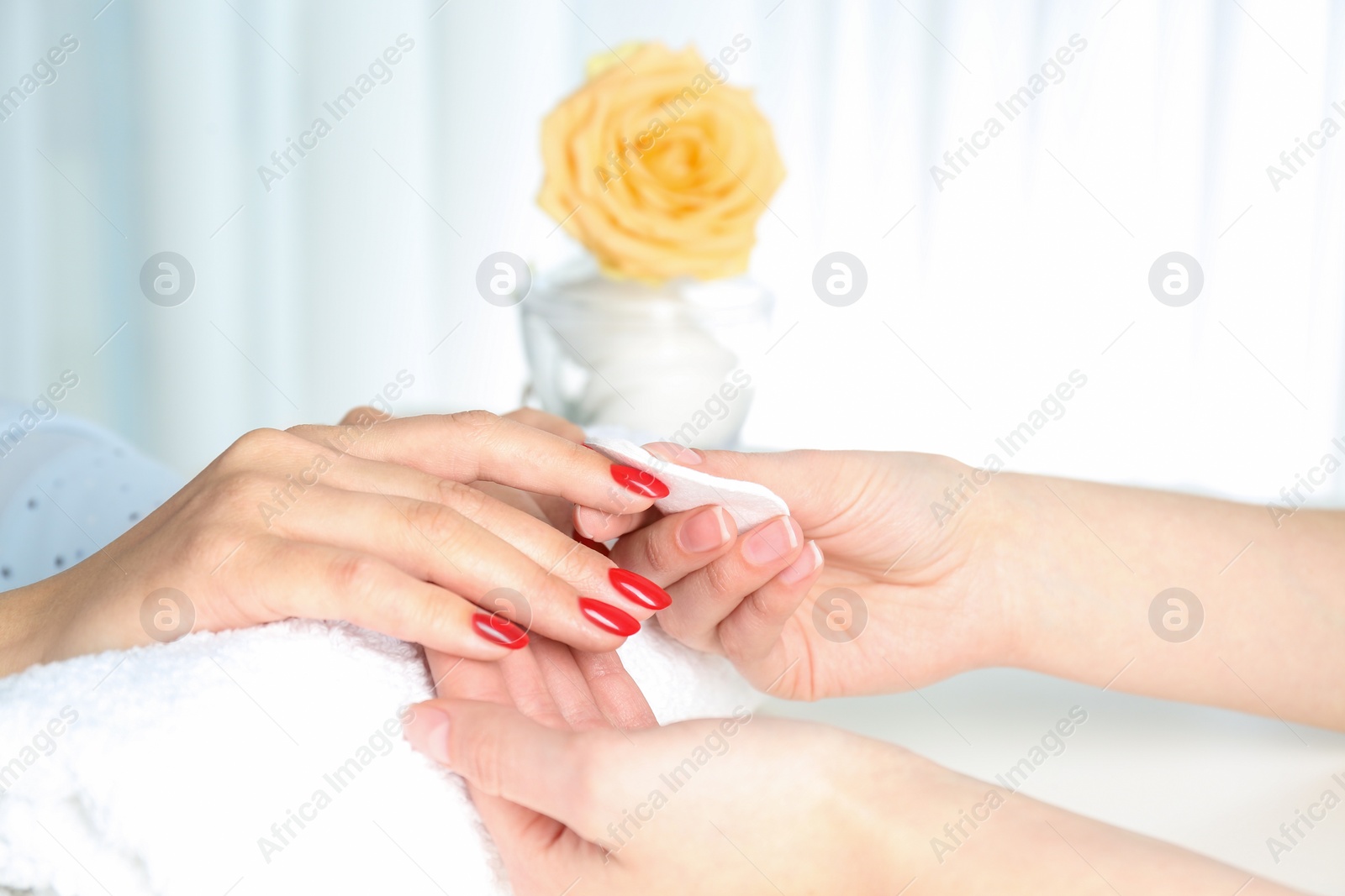 Photo of Manicurist removing polish from client's nails in salon, closeup