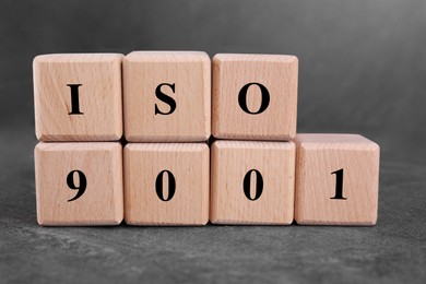 International Organization for Standardization. Cubes with abbreviation ISO 9001 on gray textured table