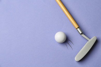 Hitting golf ball with club on lilac background - creative image. Top view