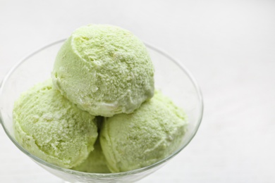 Delicious green ice cream served in dessert bowl on white table, closeup