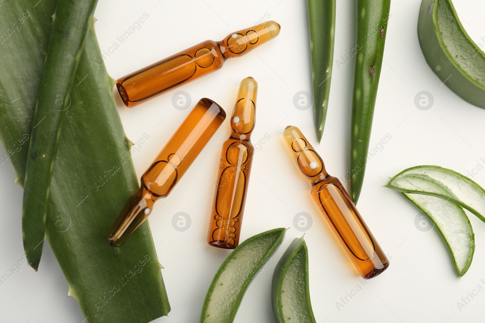 Photo of Skincare ampoules and aloe leaves on white background, flat lay