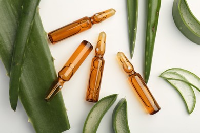 Skincare ampoules and aloe leaves on white background, flat lay