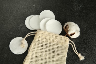 Photo of Cotton pads, bag and flower on black table, above view