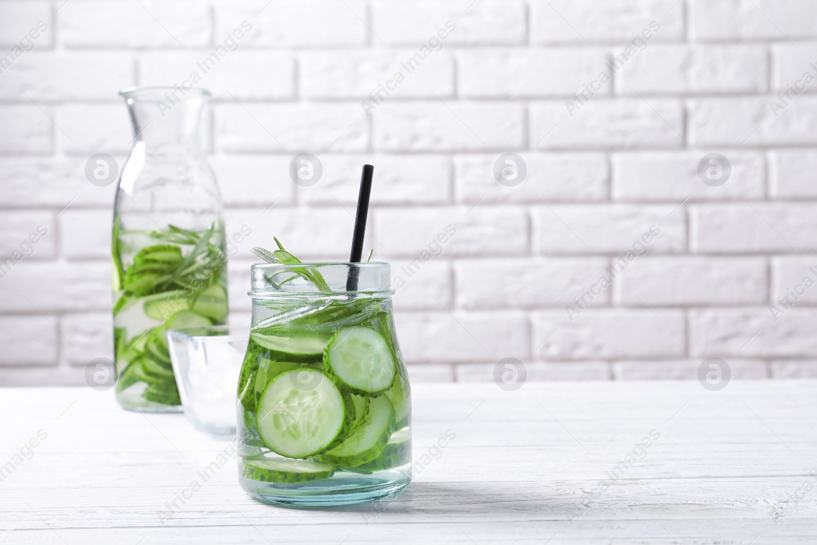 Photo of Natural lemonade with cucumber and rosemary in glassware on table