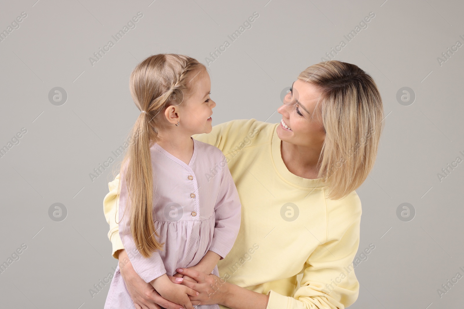 Photo of Happy mother and daughter on grey background