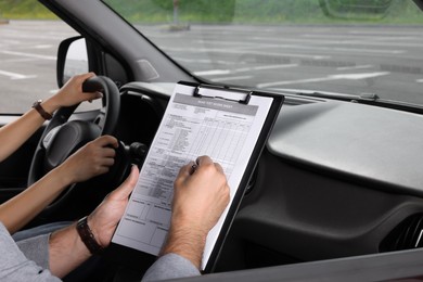 Photo of Driving school. Student passing driving test with examiner in car at parking lot, closeup
