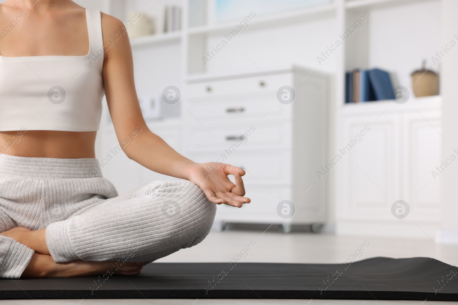 Photo of Woman practicing Padmasana on yoga mat at home, closeup and space for text. Lotus pose