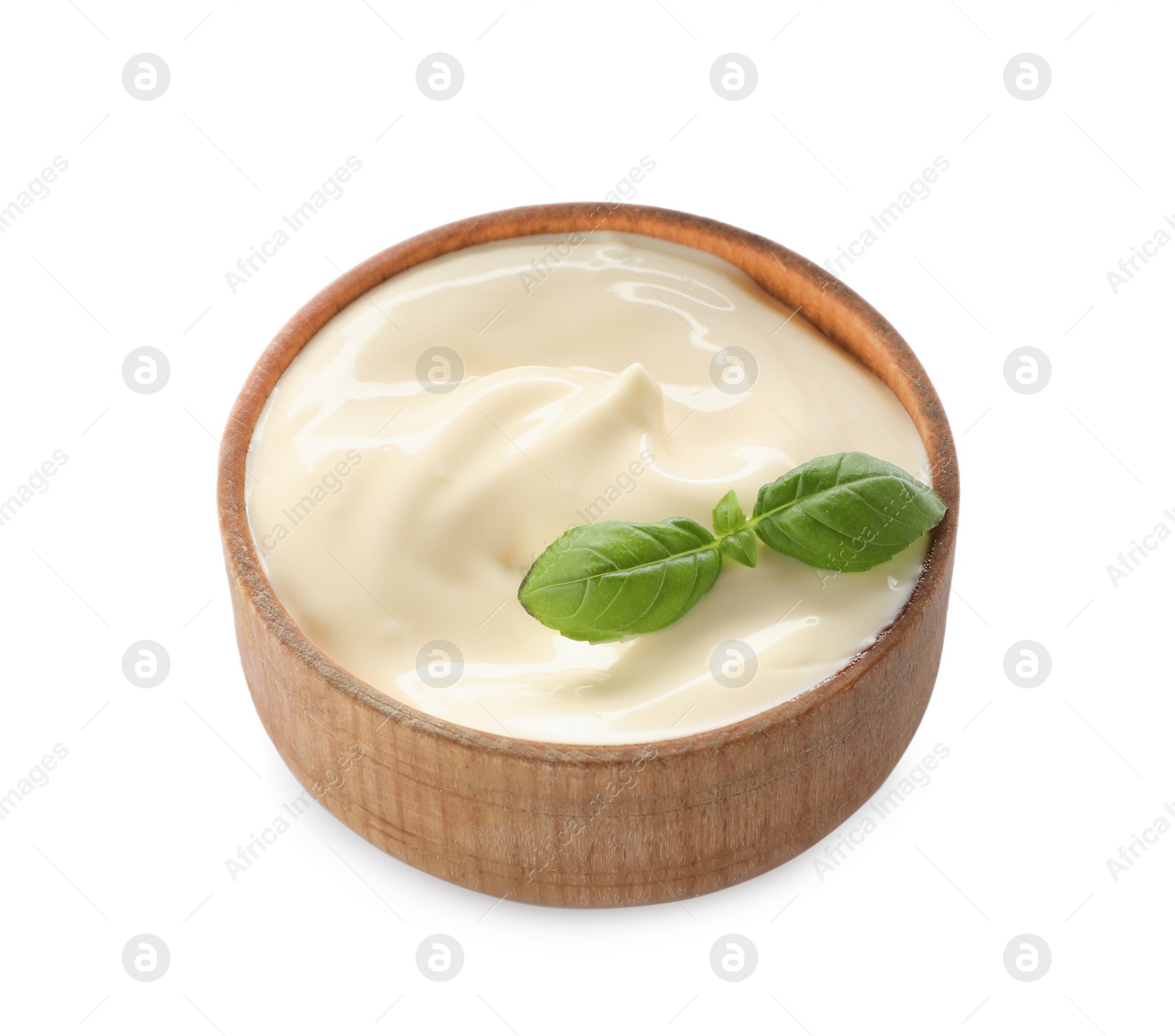 Photo of Mayonnaise with basil leaves in wooden bowl isolated on white