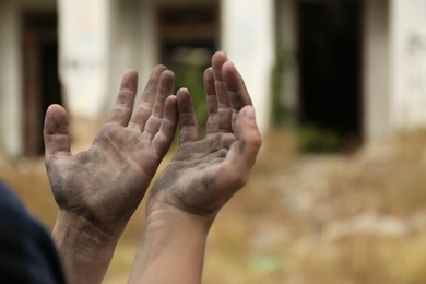 Photo of Poor homeless child begging for help outdoors, closeup