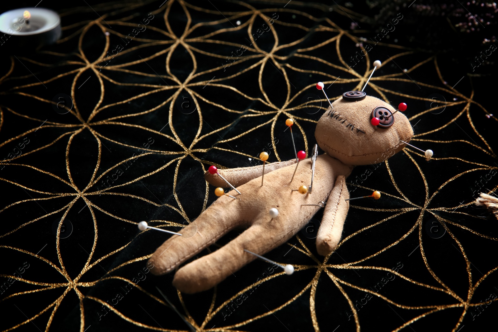 Photo of Voodoo doll pierced with pins on table. Curse ceremony