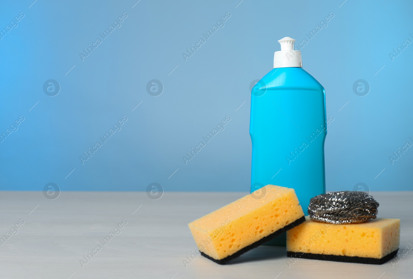 Photo of Bottle of cleaning product and supplies on light table. Space for text