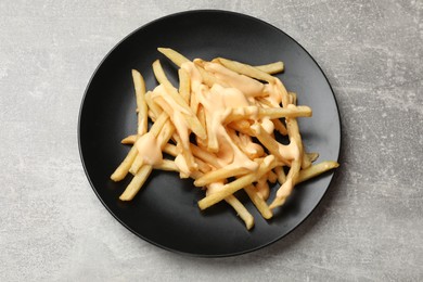 Photo of Delicious French fries with cheese sauce on grey table, top view