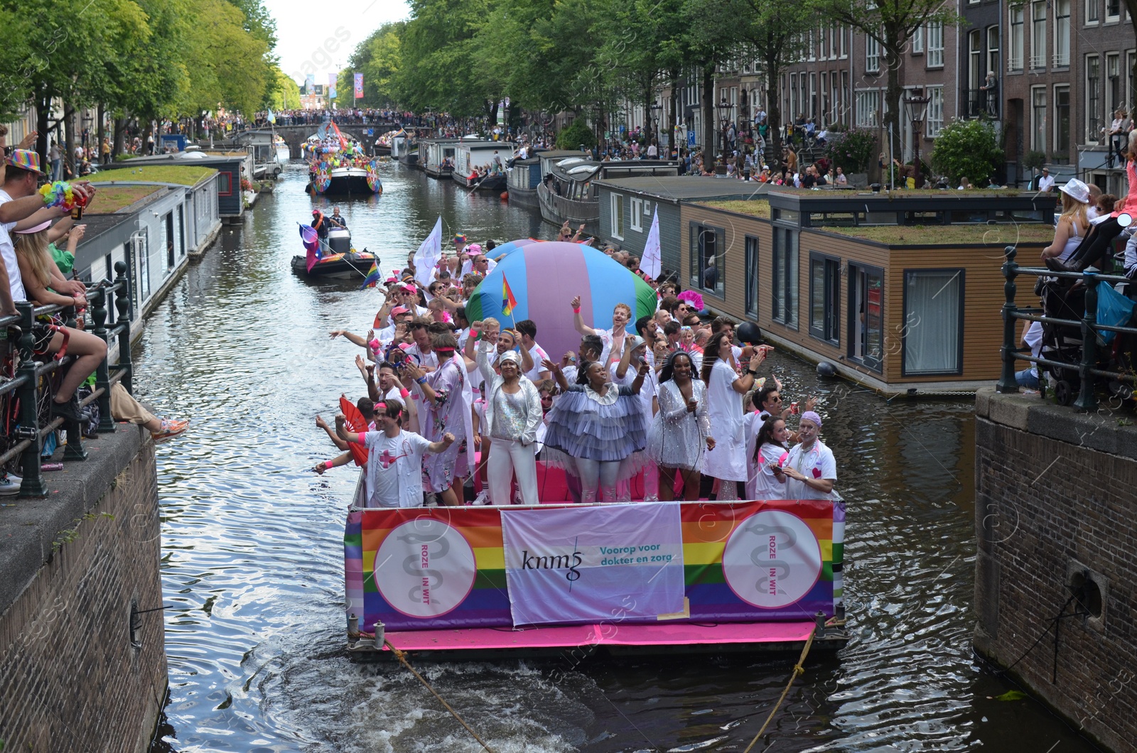 Photo of AMSTERDAM, NETHERLANDS - AUGUST 06, 2022: Many people in boats at LGBT pride parade on river